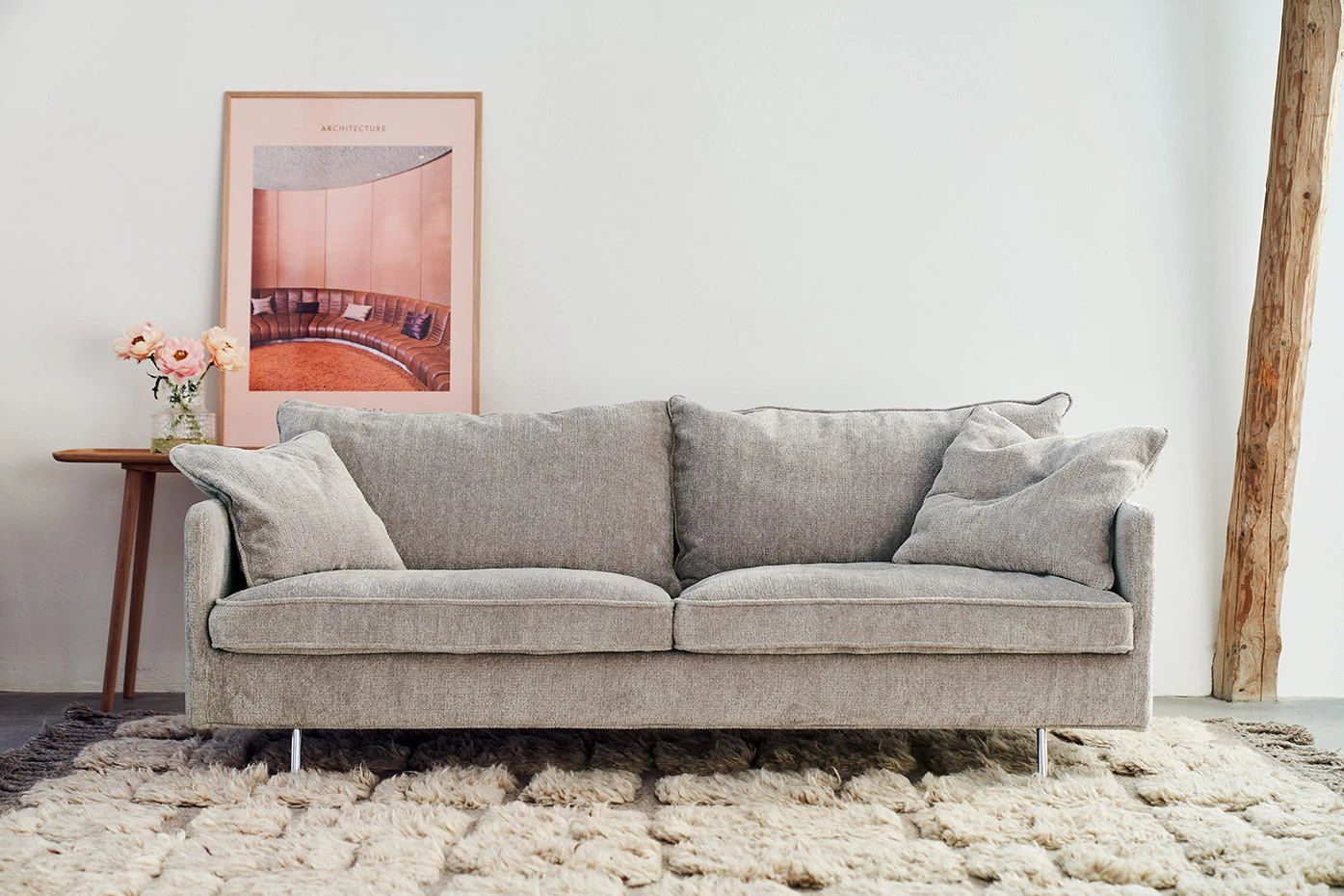 Jasnoszara trzyosobowa sofa Sits Julia na chromowanych nóżkach, na kremowym wełnianym dywanie
